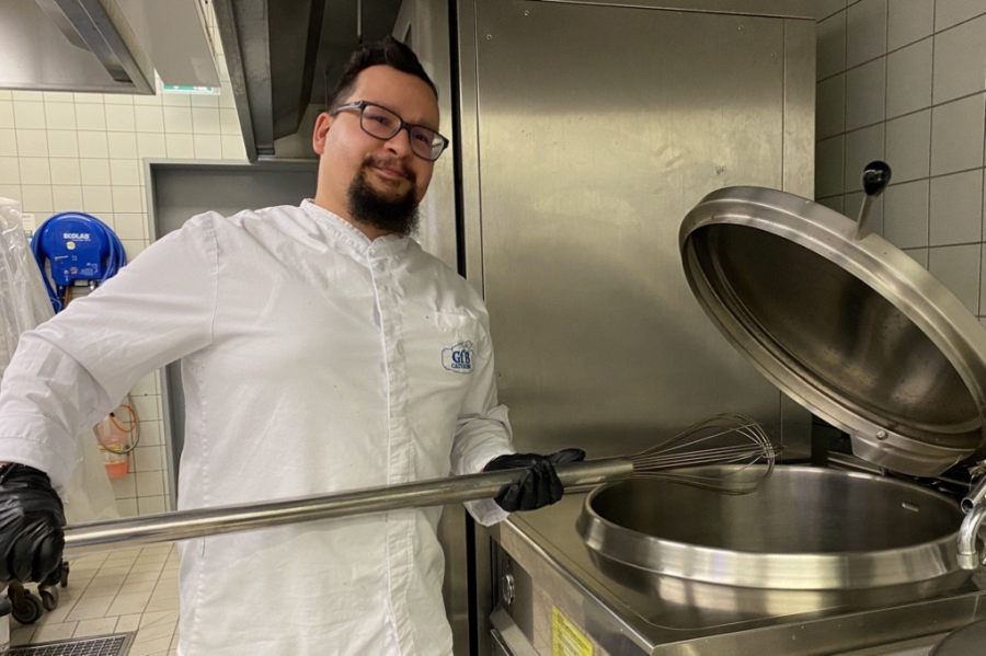 Ricardo Garces Acosta zeigt, wo am Freitagmorgen noch Vanille-Sauce für Hefeklöße zubereitet wurde: im 150-Liter Topf. Im Sportgymnasium gibt es Internatsschüler, die auch in den Ferien verköstigt werden.