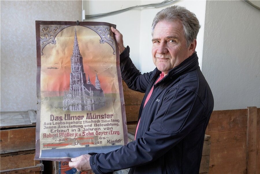 Helmut Müller, Vorsitzender des Schnitz- und Krippenvereins Geyer, zeigt ein altes Plakat, das mit einer hölzernen Nachbildung des Ulmer Münsters wiedergefunden worden ist.