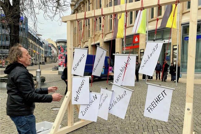 Galgen-Aktion in Plauen findet wenig Zuspruch - Thomas Knoll vom Verein Colorido befestigt symbolisch Werte an einem auf dem Postplatz aufgestellten Galgen. 
