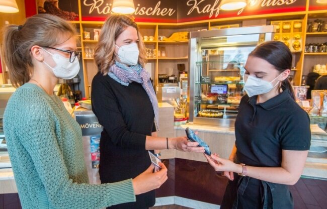 Jennifer Lubojanski, Mitarbeiterin im "Café am Stern", kontrolliert die 2G-plus-Nachweise von Juliane (links) und Daniela Drews. 
