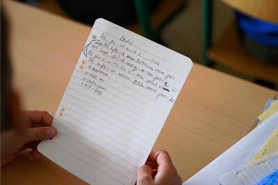 Geflüchtete aus der Ukraine: Zu wenige Lehrer für zu viele Kinder in Auerbach? - Ein Symbolbild: Ein Grundschüler aus der Ukraine hält im Deutschunterricht einen Zettel mit Schreibübungen in der Hand.