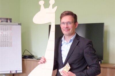 Gemeinde Claußnitz heißt Babys willkommen - Bürgermeister Andreas Heinig zeigt die Begrüßungsgeschenke der Gemeinde für Neugeborene in Claußnitz. Eine Messlatte aus Holz fürs Kinderzimmer, die als Giraffe gestaltet ist, und 50 Euro.