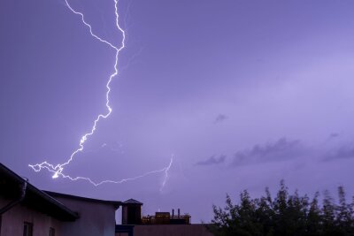 Gewitter und Sommerhitze in Sachsen - Ein Blitz entlädt sich über einem Wohngebiet.
