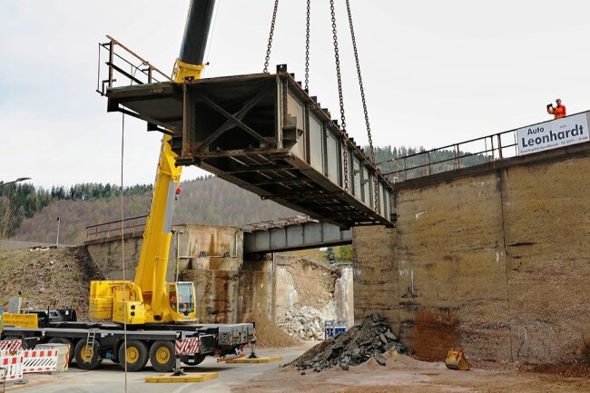Kurz nach 10 Uhr schwebt der erste Metallträger der alten Eisenbahnbrücke zu Boden. Für 6,5 Millionen Euro will die Erzgebirgsbahn eine neue, schlanke Gleisbrückenkonstruktion errichten. 
