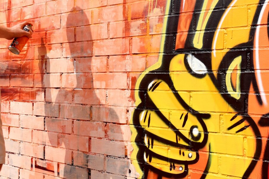 Graffiti-Entfernung kostet Dresden rund 70.000 Euro pro Jahr - Ein Sprayer besprüht eine Mauer.