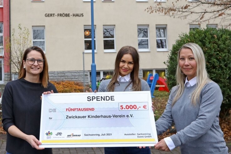 Kristin Valverde Dominguez (Mitte) und Conny Bockwitz von der Sachsenring Event-Gesellschaft übergeben einen Spenden-Scheck an Hausleiterin Sandra Popadak (links) vom Zwickauer Kinderhaus-Verein. 