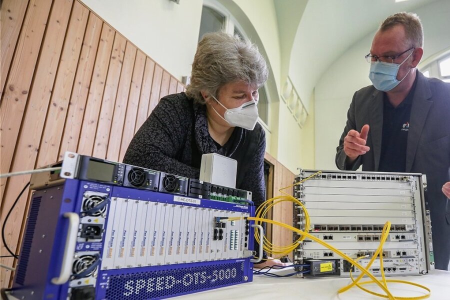 Die Schulleiterin der Grundschule Rabenstein, Katrin Jechorek und Patrick May von Eins Energie schauen sich Technik an: Diese neue Verteilstation versorgt Haushalte mit schnellem Internet aus Glasfaser-Kabeln. 