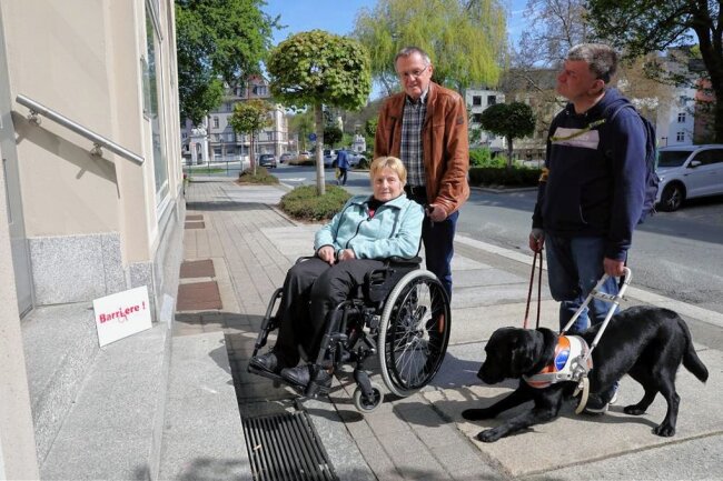 Härtetest mit Rolli und Blindenhund in Aue: Wo Menschen mit Handicap in der Stadt auf Barrieren stoßen - Vor diesem Eingang mit Treppen an der Poststraße in Aue geht es für Gisela Kühnel, die auf einen Rollstuhl angewiesen ist, erst einmal nicht weiter. Ihr Mann Erhard kennt die Probleme. Für Daniel Pilz sind fehlende taktile Leitsystem ärgerlich. 