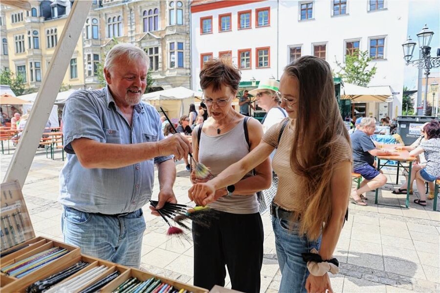 Handwerkermarkt in Zwickau: Wenn ein Rasierpinsel mehr als 100 Euro kostet - Pinselmacher Karl Dommel zeigt den Besucherinnen Constanze (links) und Joane Naundorf, wie weich Pinsel sein können.