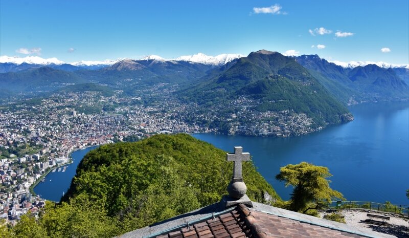 Hart an der Grenze -  Grandioses Panorama: Blick vom Monte San Salvatore auf Lugano und den Luganer See. Irgendwo im Grün und Blau verläuft die Grenze zu Italien. 