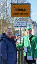Hat Gelenaus Ortschef seine Wette erfüllt? - Gelenaus Bürgermeister Knut Schreiter zeigt Yannic Cyffka, dem Vorsitzenden des 1. Gelenauer Carnevalsclubs, das neue Schild am Orteingangsschild. 