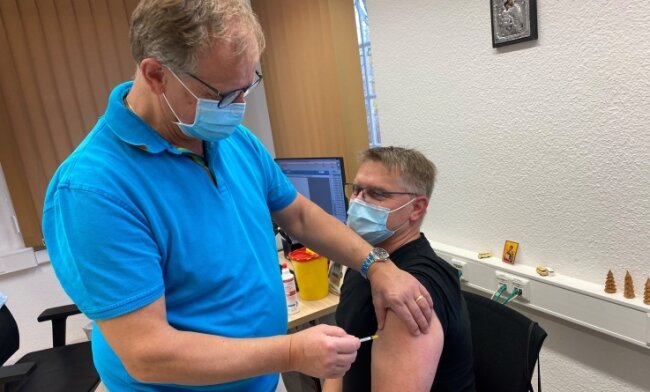Dr. Jan Anastassis Skuras impft in seiner Praxis in Lichtenwalde den 48-jährigen Jens Gräbner. Der Chemnitzer erhält seine Booster-Impfung. 
