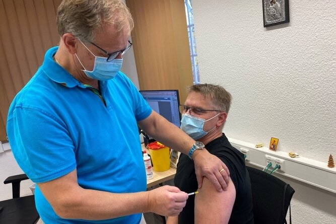 Dr. Jan Anastassis Skuras impft in seiner Praxis in Lichtenwalde den 48-jährigen Jens Gräbner. Der Chemnitzer erhält seine Booster-Impfung. 