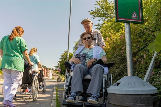 Die Hecke und wuchtige Haltestellenaufsteller sorgen dafür, dass Heinz Hammer mit der im Rollstuhl sitzenden Ehefrau Marlies (rechts) nicht den Fußweg passieren kann. Dann muss er auf die Parkstraße ausweichen, wie es auch die Alltagsbegleiterinnen vom K & S-Heim oft tun. 