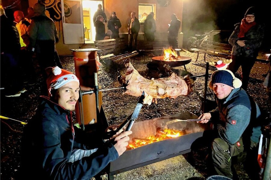 Helbigsdorfer Jugendclub geht in die Vollen - Nico Linke und Maikel Goedtke (r.) beim Grillen des Schweins am Spieß bei der Weihnachtsfeier für die Helbigsdorfer. 