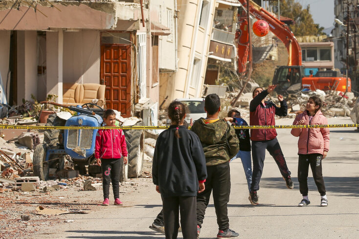 Samandag ( Türkei): Kinder spielen mit einem Ball neben zerstörten Gebäuden. Die Überlebenden des Erdbebens, das die Türkei und Syrien erschütterte und bei dem Zehntausende von Menschen ums Leben kamen und Hunderttausende obdachlos wurden, sind erneut Opfer eines weiteren tödliches Nachbebens geworden, welches die Region erschütterte.