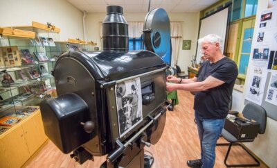 Historische Filmtechnik funktioniert noch immer - Joachim Siegert, ehemaliger Leiter des Auerbacher Kinos, beim Einrichten des alten Projektors der Einrichtung. Das historische Schwarz-Weiß-Foto im Vordergrund zeigt ihn bei derselben Tätigkeit in den 1970er-Jahren. 
