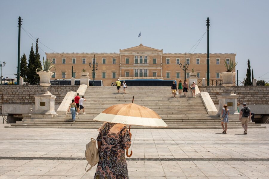 Hitzewelle in Griechenland und der Türkei - Eine Frau schützt sich mit einem Sonnenschirm  auf dem Syntagma-Platz in Athen vor der Sonne.