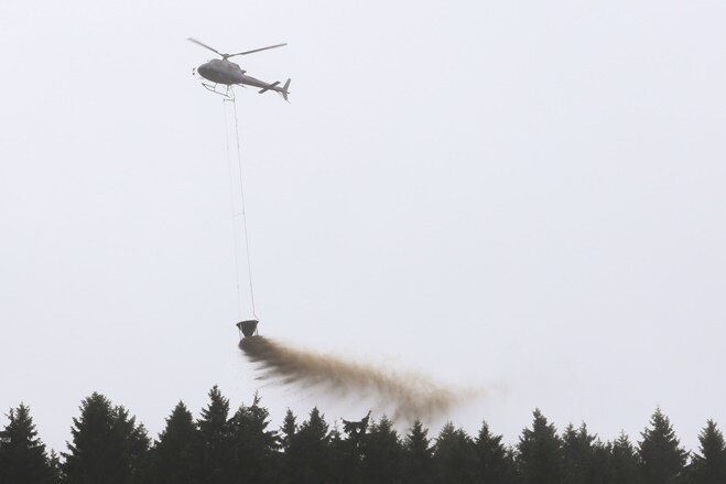 Hubschrauber werfen Kalk über Waldgebiet ab - 