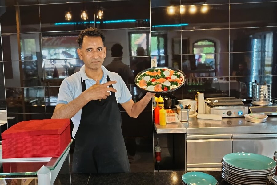 In Bienenmühle gibt es nun Pizza, Pasta und Baguette - Der Gastronom Saeed Shah zweigt stolz seine Pizza Tonno. Bürgermeister Michael Funke gratuliert dem Gastronom zur Eröffnung seines Imbisses.