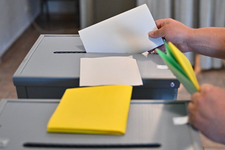 In Sachsen zeigt sich eine ähnliche Wahlbeteiligung wie 2019 - Eine Person steckt seinen Wahlzettel zu Europawahl in eine Wahlurne.