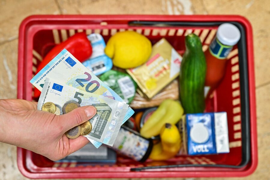Inflation fällt auf 2,2 Prozent - - Eine Frau hält auf ihrer Hand Geldscheine vor einem Korb mit Einkäufen
