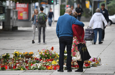 Internationale Pressestimmen zu Chemnitz - Passanten stehen am Tatort an der Brückenstraße, an dem zahlreiche Blumen und Kerzen niedergelegt wurden. 