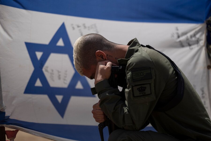 Israel in der Isolation: Zwischen Trotz und Durchhaltewillen - Ein israelischer Soldat neben der Nationalflagge: Gibt es für Israel einen Ausweg aus dem Schlamassel?