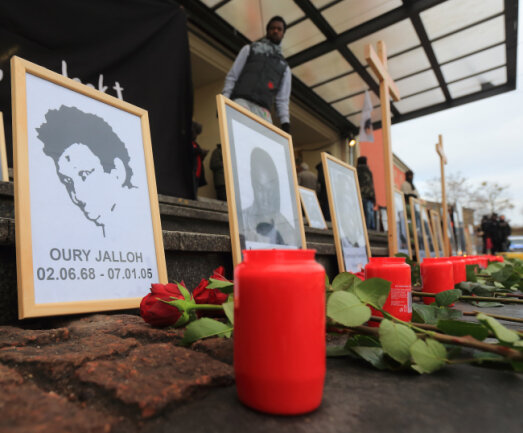 Jalloh-Ermittlungen bleiben eingestellt - kein Hinweis auf Mord - n einem Bild des Asylbewerbers Oury Jalloh (l) sind vor Beginn einer Demonstration zu seinem zehnten Todestag 2015 Blumen und Kerzen aufgestellt.