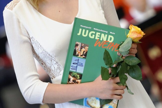 Eine Jugendliche mit einer gelben Rose und dem aktuellen Buch für die Jugendweihe-Teilnehmer. 