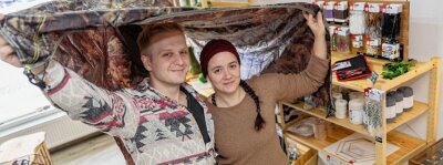 Junges Paar öffnet Outdoor-Laden - Patrick Leonhardt und Laura Knape mit dem Tarp, das man zum Übernachten im Wald aufspannen kann.