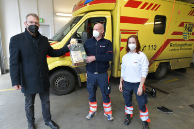 Kaffee für die Feuerwehr: Freibergs OB verteilt an Heilig Abend Geschenke - Oberbürgermeister Sven Krüger überreicht ein Geschenk an Rene Freudrich und Celeste Rochlitzer vom Malteser Hilfsdienst. 