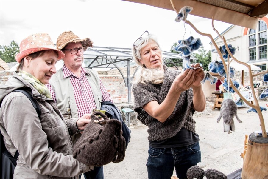 Kaum Gewinn am Ende des Tages: Warum Händler des Naturmarktes in Olbernhau trotzdem glücklich sind - Ines Richter (rechts) zeigt Ramona und Gerd Gröger ihre selbst hergestellten Waren aus Naturwolle.
