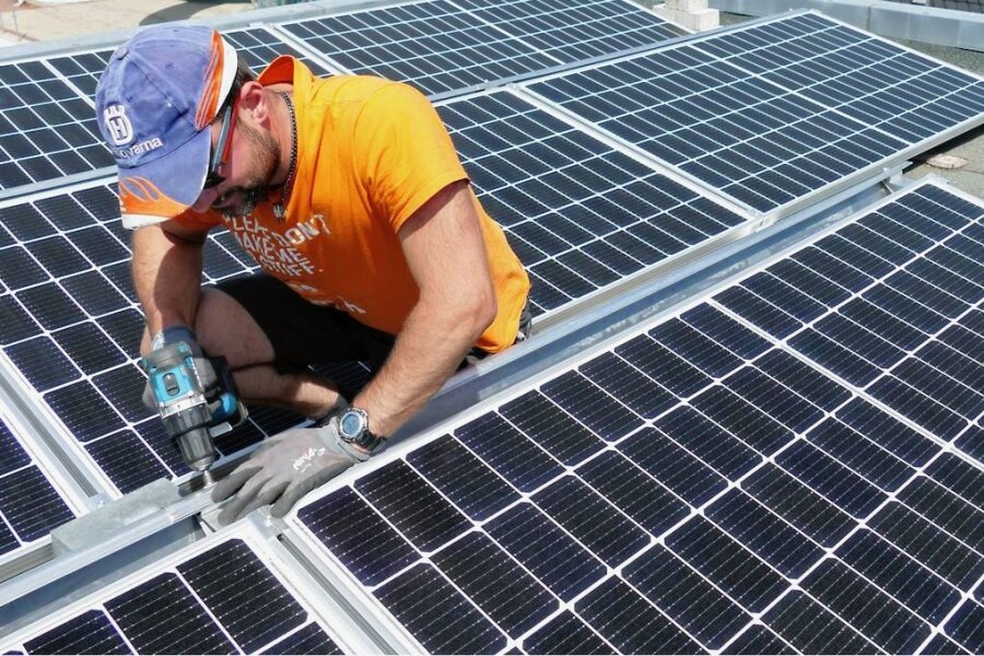 Kein Saft: Warum neue Fotovoltaikanlagen im Erzgebirge nicht in Betrieb gehen - Fotovoltaik boomt im Erzgebirgskreis: Hier ein Handwerker bei der Installation von PV-Modulen 2022 im Burkhardtsdorfer Freibad.