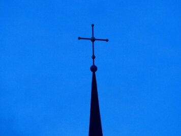            Ein Kreuz ist an einer Kirchturmspitze zu sehen.