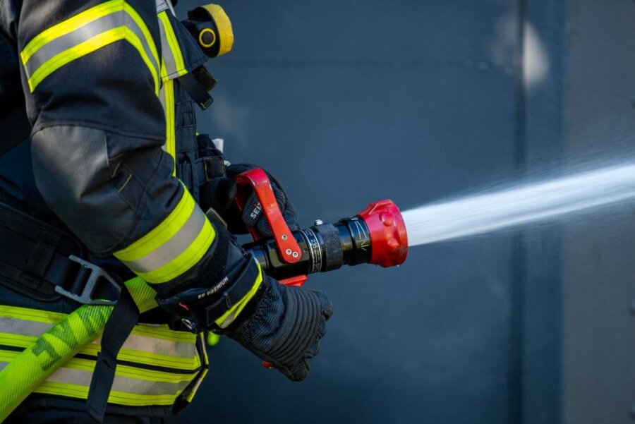 Kellerbrand in Reichenbach - Ein Mitglied der Feuerwehr spritzt aus einem Schlauch mit Wasser.