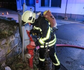 Kellerbrand macht Haus unbewohnbar - Ein Feuerwehrmann schließt den Hydranten an. 
