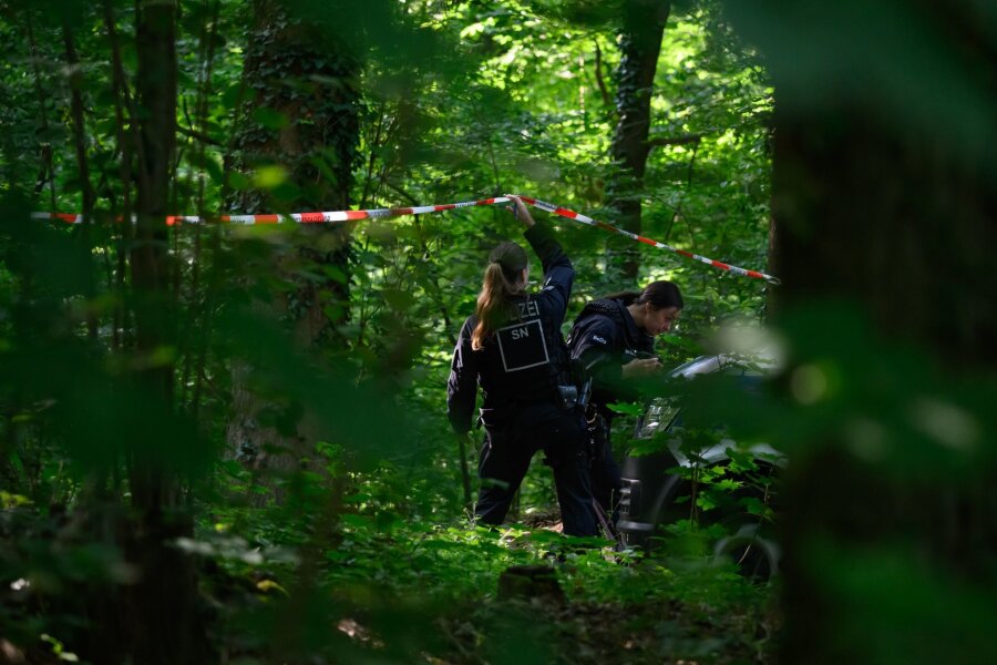 Kind getötet: Mordkommission sucht auch "im engeren Umfeld" - Eine Polizistin hält in einem Wald Absperrband hoch.