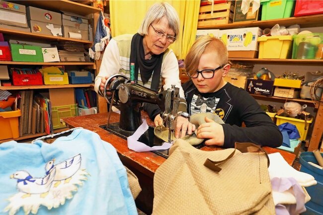 Horterzieherin Elisabeth Zimmer hilft dem zehnjährigen Lino Haegler an einer alten Singer-Nähmaschine.