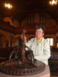 Klang für Orgel und Glocken - Evelyn Ziegelt, kirchliche Mitarbeiterin, am Taufstein in der Schwarzbacher Kirche. Orgel und Glockengeläut sollen überholt werden.