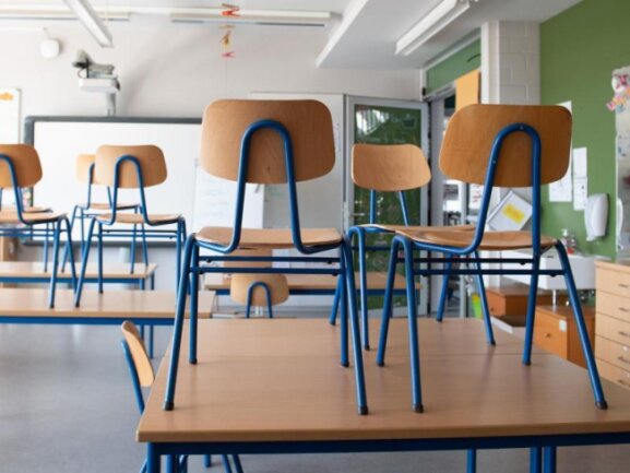            Stühle stehen in einer Schule auf den Tischen.