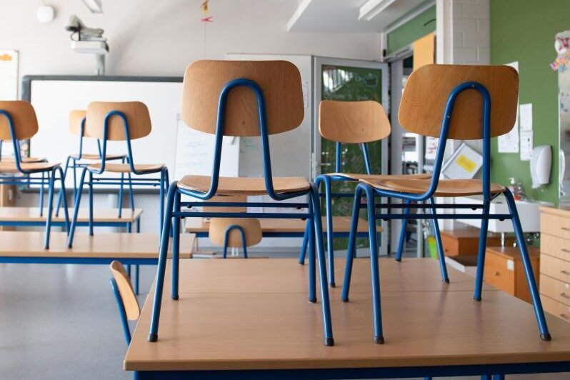            Stühle stehen in einer Schule auf den Tischen.