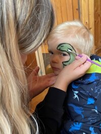 Kleiner Verein krempelt fürs Dorf die Ärmel hoch - Der zweijährige Wim lässt sich von Franziska Müller einen Saurier ins Gesicht schminken. 