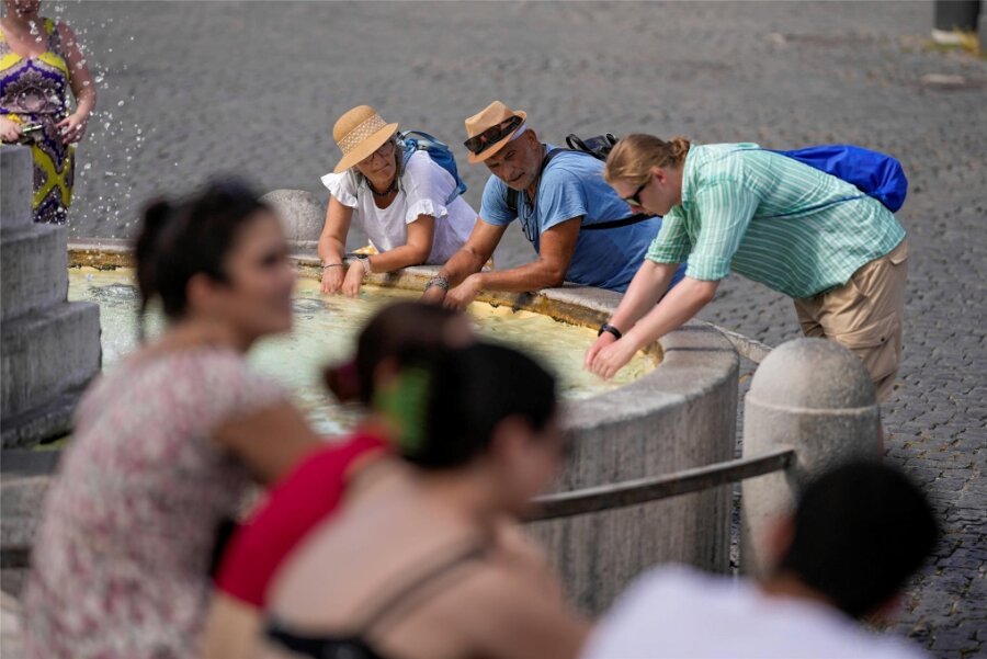 Klimakrise bedroht beliebte Reiseländer - Puh, ist das heiß: Touristen erfrischen sich bei ihrem Rombesuch an einem Brunnen. 