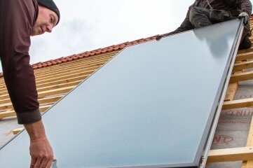 Kollektoren kommen per Kran - Für die Solarthermieanlage wurden 16 Sonnenkollektoren auf dem Dach montiert.