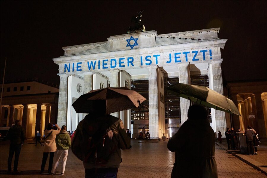 Kommentar zum Antisemitismus: Jung, jüdisch – in Gefahr - Der Schriftzug „Nie wieder ist jetzt“ wird zum 85. Jahrestag der Pogromnacht an das Brandenburger Tor projiziert. Antisemitische Vorfälle sind in der Bundesrepublik stark angestiegen.
