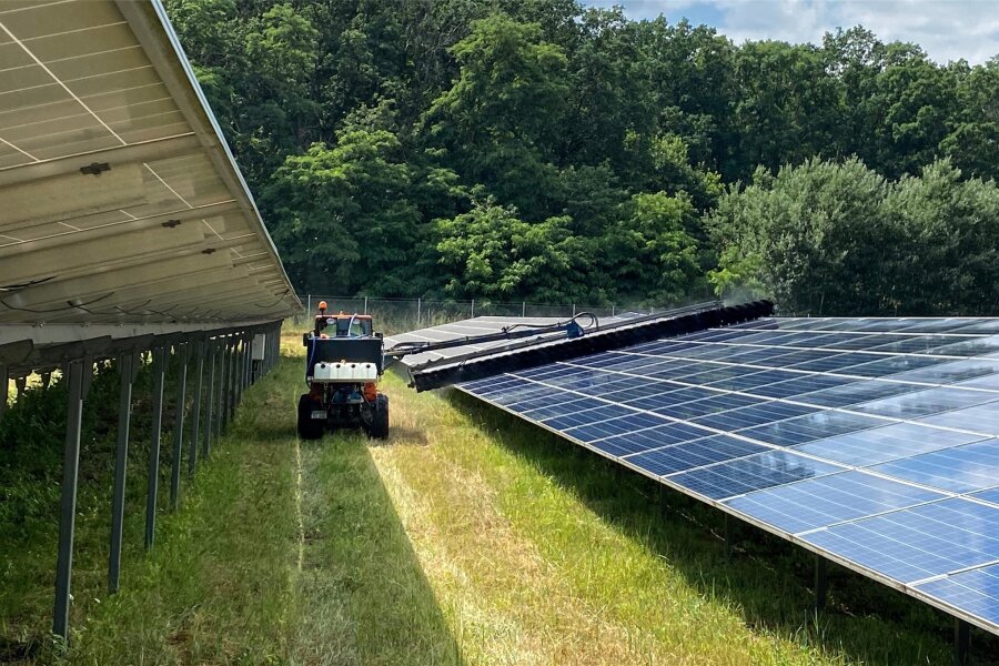 Kommentar zum Solarpark Mittelsaida: Stummer Schrei? - Symbolbild: In einem Solarpark wird das Gras zwischen den Panellreihen gemäht.