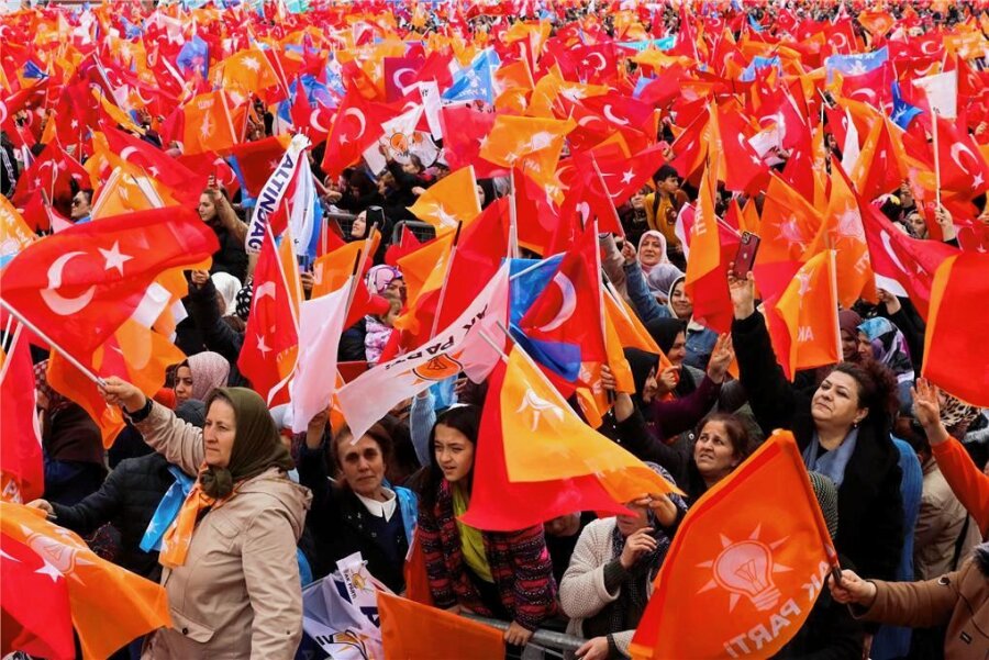 Kopf-an-Kopf-Rennen in der Türkei: "Türkische Wähler in Deutschland haben großen Einfluss" - Menschen schwenken türkische Flaggen und Fahnen der regierenden AK-Partei, während sie dem türkischen Präsidenten Erdogan bei einer Wahlkampfveranstaltung in Ankara zuhören. 