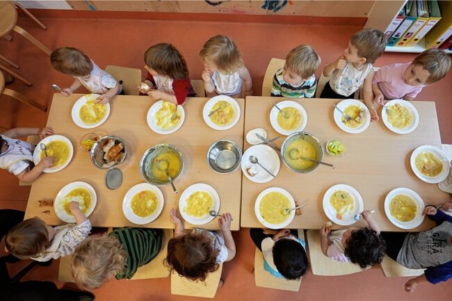 Kostenloses Mittagessen: Damit Kinder in Sachsen weniger kosten - Krippen-Kinder nehmen gemeinsam ihr Mittagsessen ein. Dafür soll es für die Eltern jetzt finanzielle Entlastungen geben. 