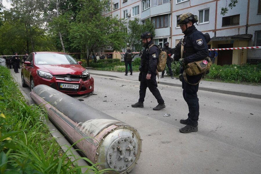 Krieg gegen die Ukraine: So ist die Lage - Polizisten inspizieren einen Teil einer russischen Rakete, die in der Nähe eines Wohnhauses in Charkiw eingeschlagen ist.